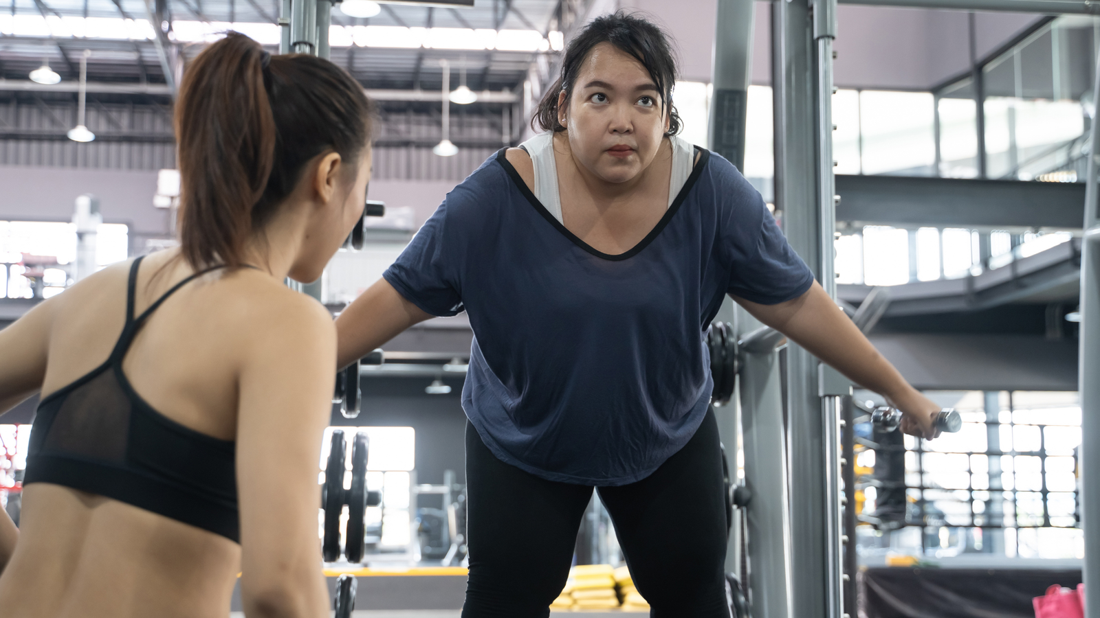 Personal trainer guiding a client through a workout session, illustrating the importance of understanding your target audience in the fitness industry.